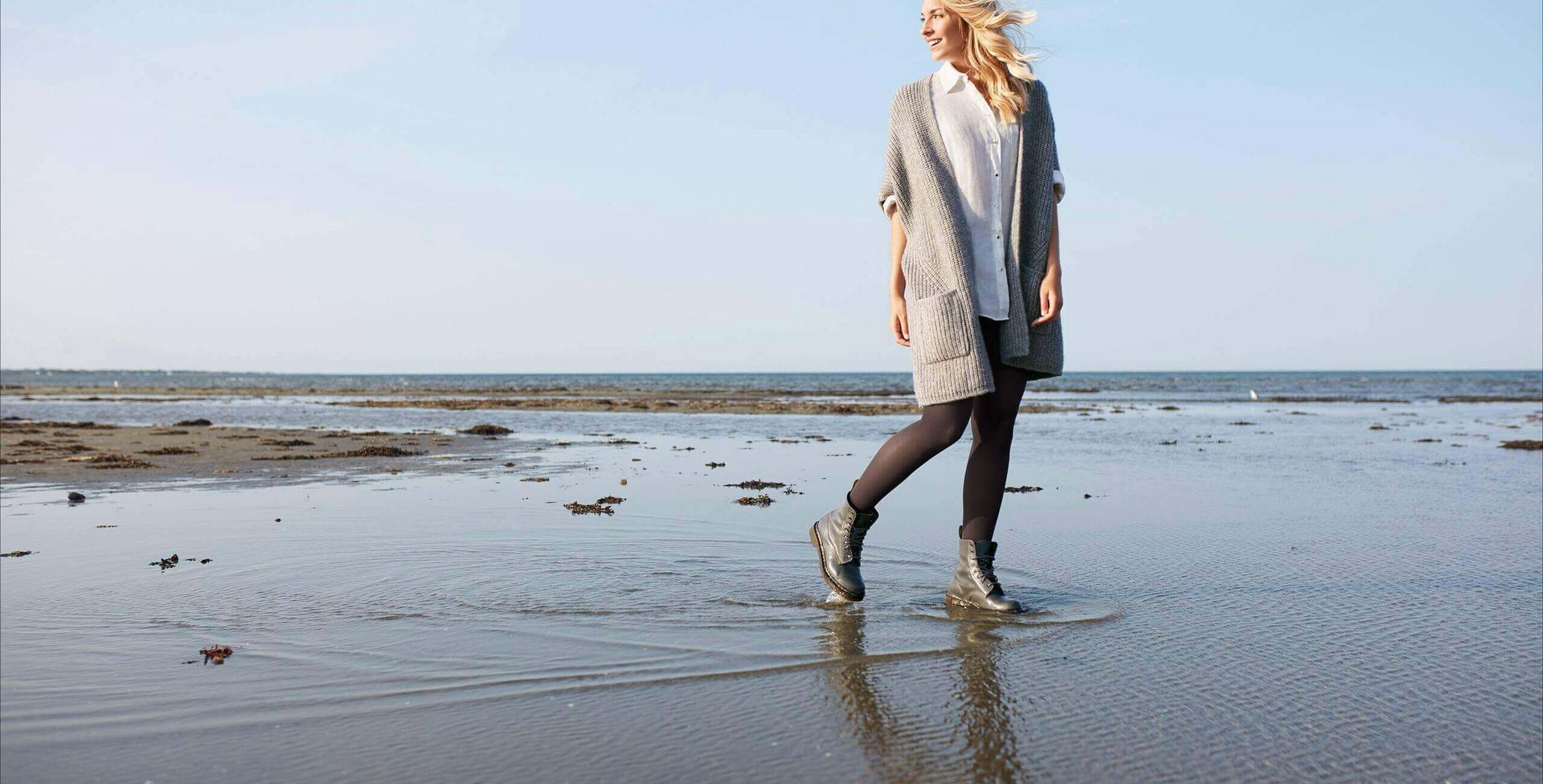 Eine junge Frau läuft an einem Meeresstrand entlang. Sie trägt schwarze Kompressionsstrümpfe von Bauerfeind. Diese fördern die Durchblutung und wirken der Entstehung von Krampfadern sowie Besenreisern entgegen.