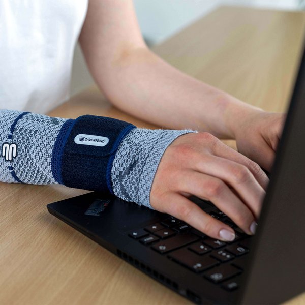 Bildausschnitt einer Frau am Laptop, die am rechten Handgelenk eine ManuTrain Bandage von Bauerfeind trägt. Diese bietet Unterstützung bei Mausarm-Beschwerden.