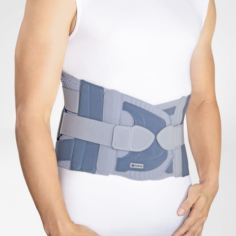 Persoon met een grijze rugbrace om de onderrug over een wit mouwloos shirt.