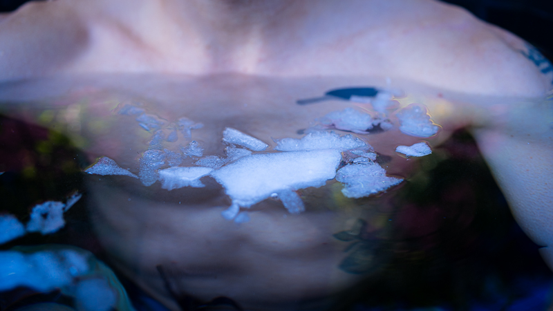 Close-up van het bovenlichaam van een persoon tijdens ijsbaden, ijsschotsen drijven op het wateroppervlak voor de borst.