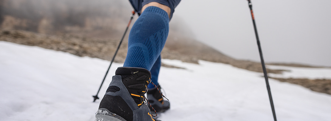 Persoon wandelt via met sneeuw bedekte rotsen. Ze draagt ​​Merino -wandelsokken