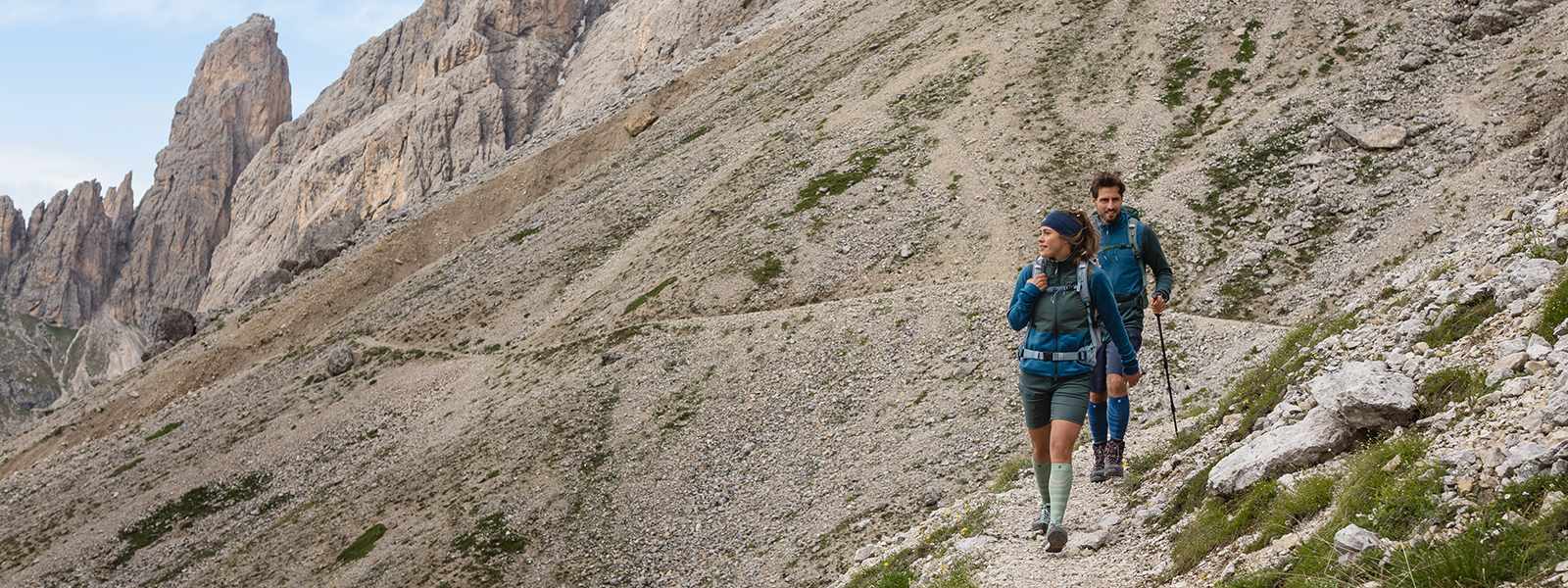 Man en vrouw wandelen een berg af met wandelstokken in de hand en dragen wandelsokken