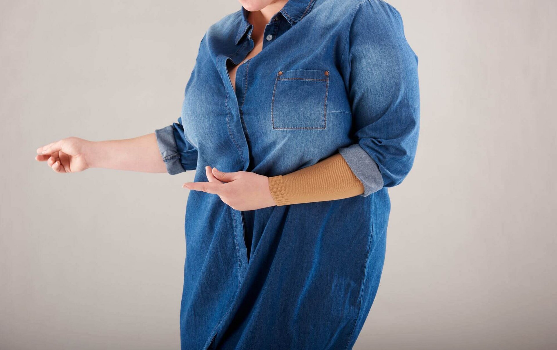 Detailopname van een vrouw met een spijkerblouse en de curaflow-platbreicompressie van Bauerfeind aan de linkerarm.