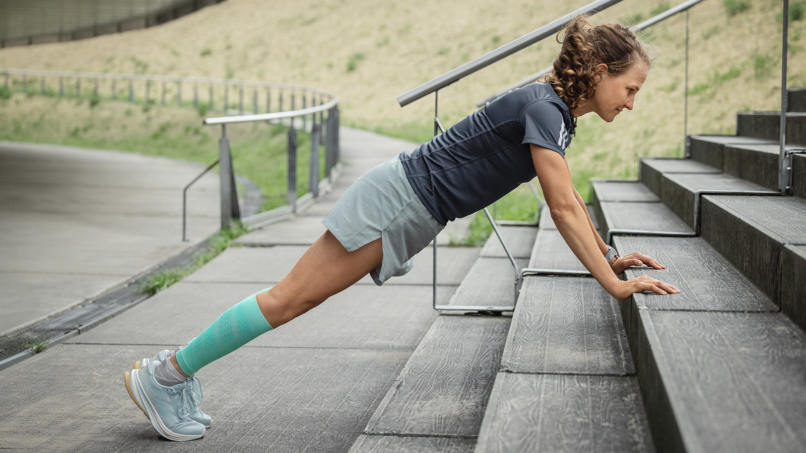 Vrouw maakt push-ups op een betonnen vloer op de achtergrond die een man uitstrekt op een muur