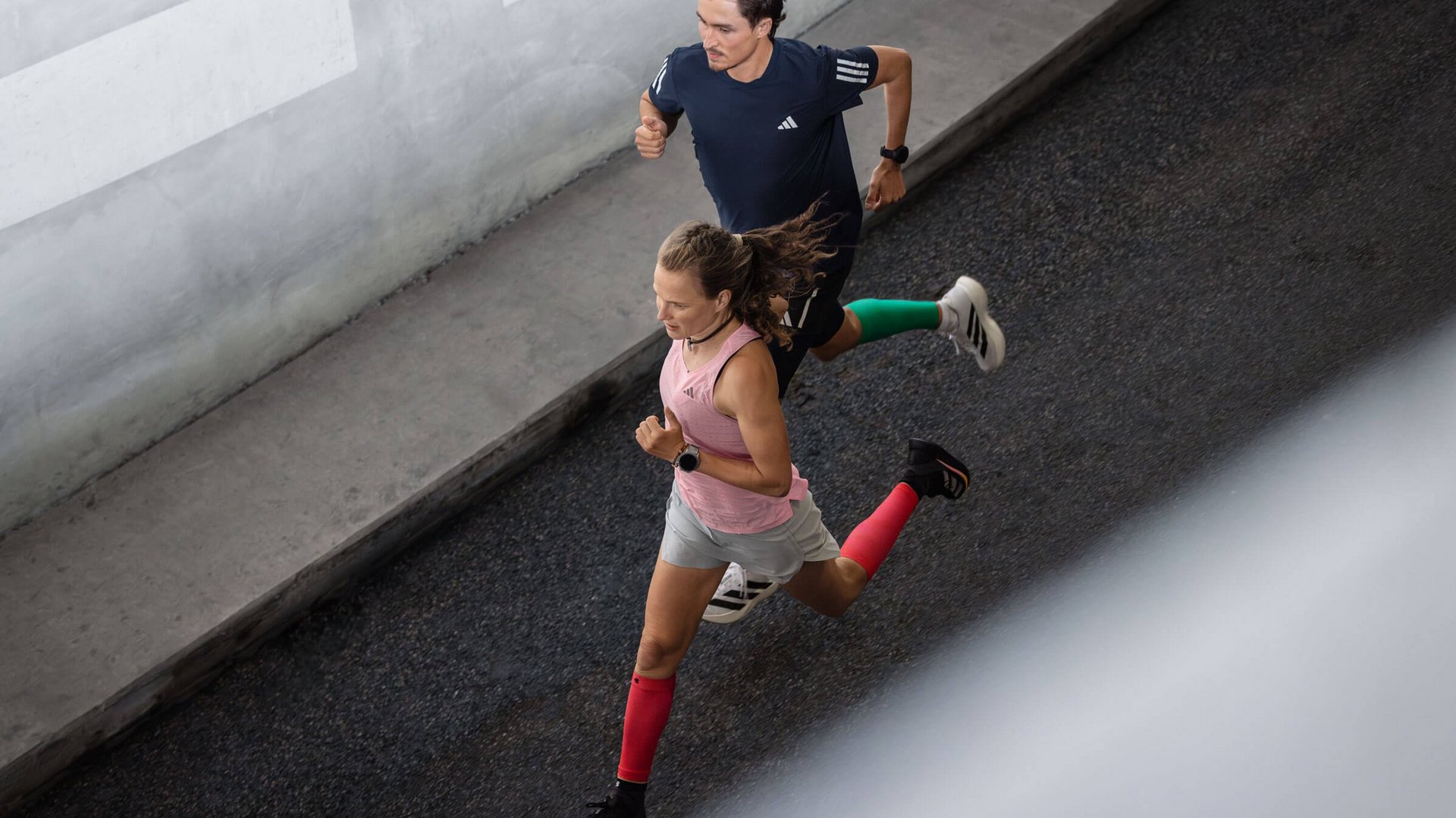 Twee hardlopers met compression sleeves van Bauerfeind rennen een straat af.