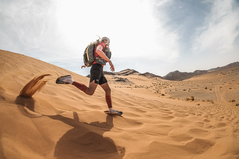 Ultraloper tijdens het lopen door zandduinen in een uitgestrekt woestijnlandschap