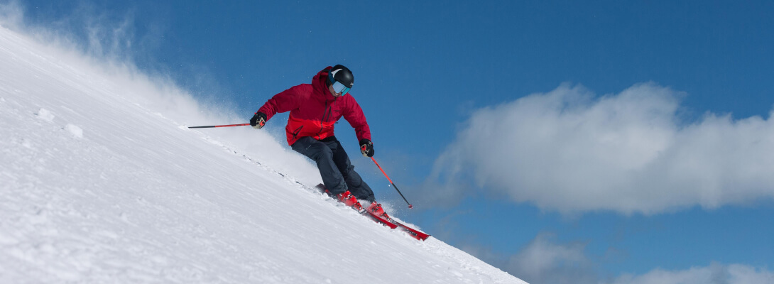 Skiër met rode jas in poedersneeuw tijdens het skiën