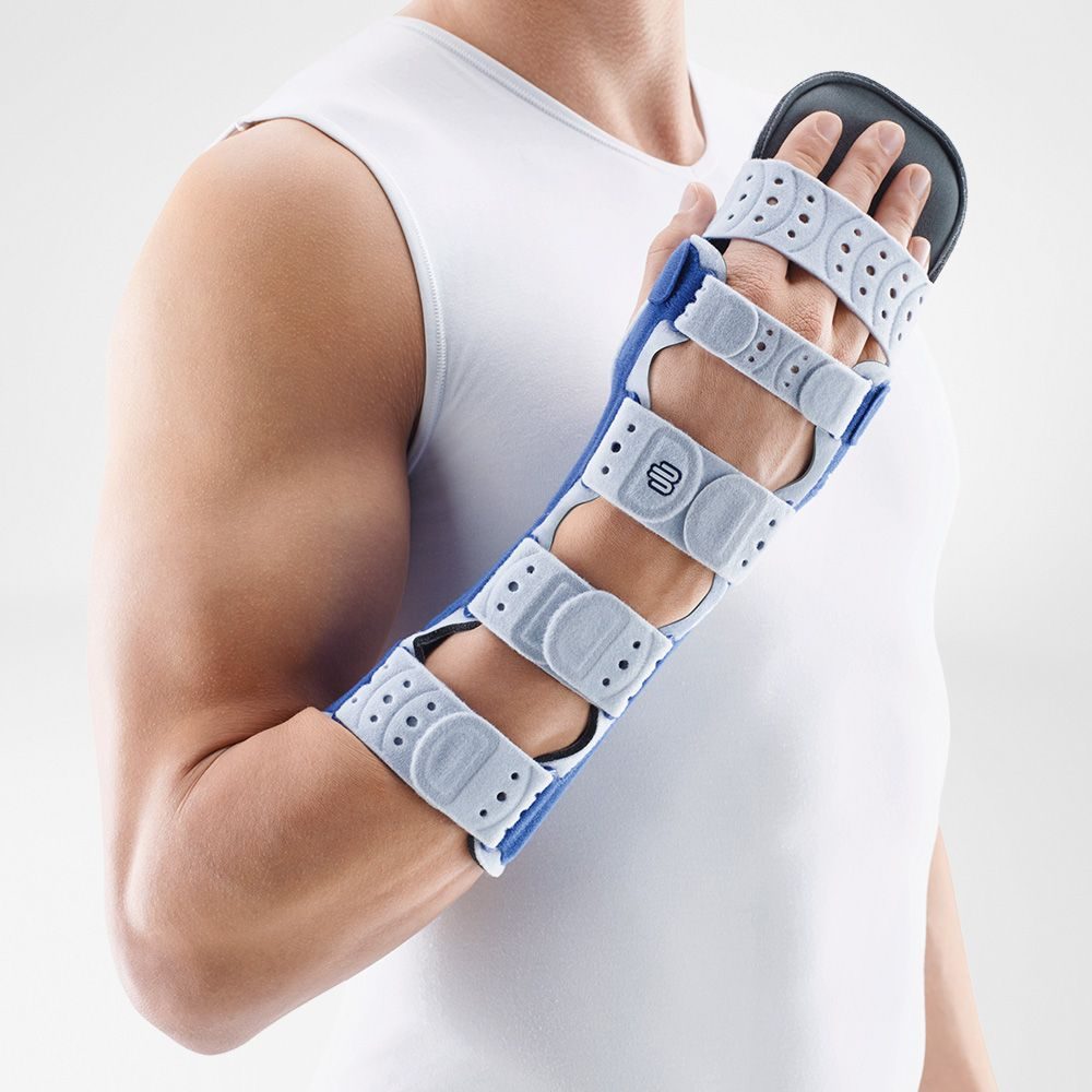 Persoon met witte mouwloze top draagt een verstelbare spalk om hand, pols en onderarm.