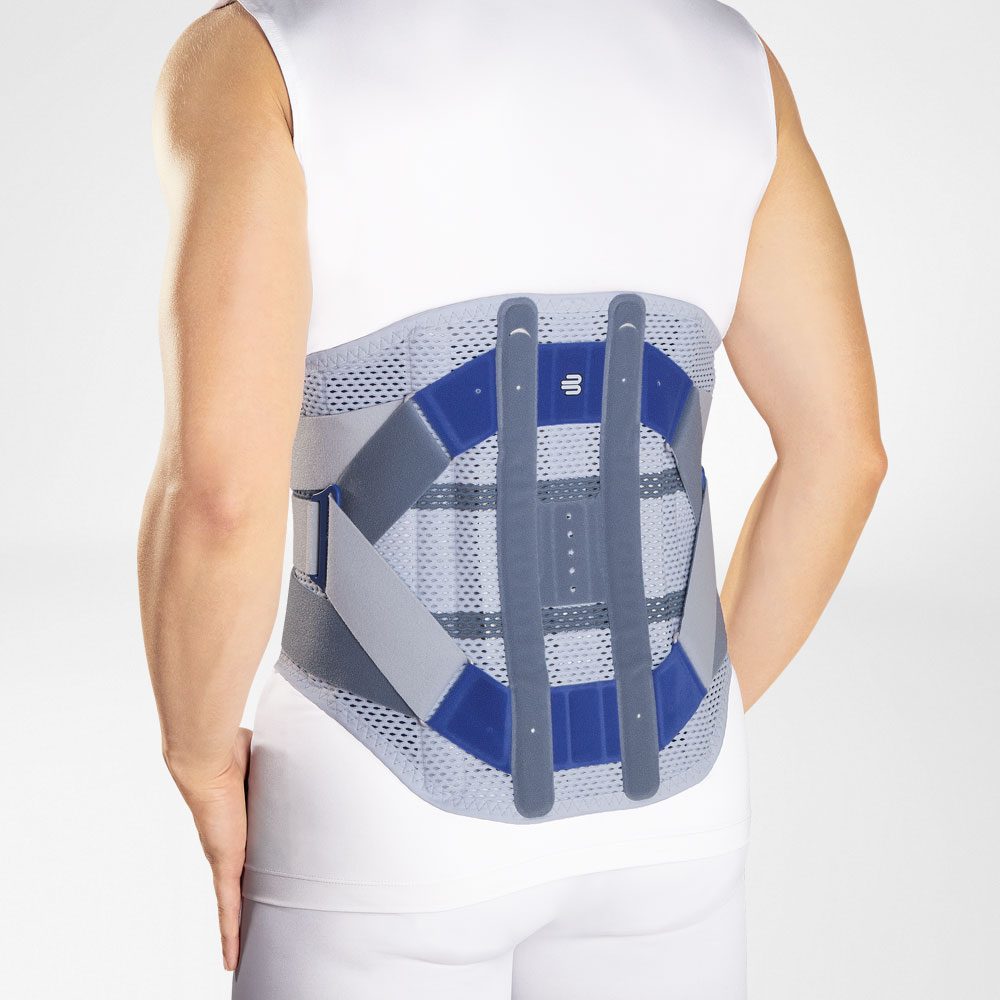Persoon van achteren met een grijs-blauwe rugbrace rond de onderrug over witte kleding.
