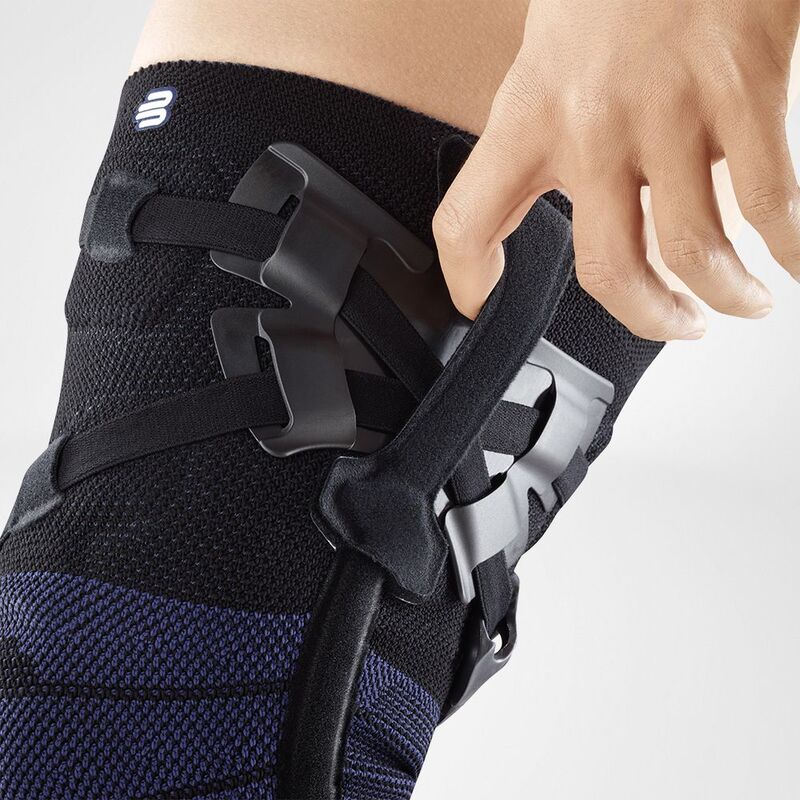 Close-up van persoon die zwarte GenuTrain OA unloader kniebrace met straps verstelt.