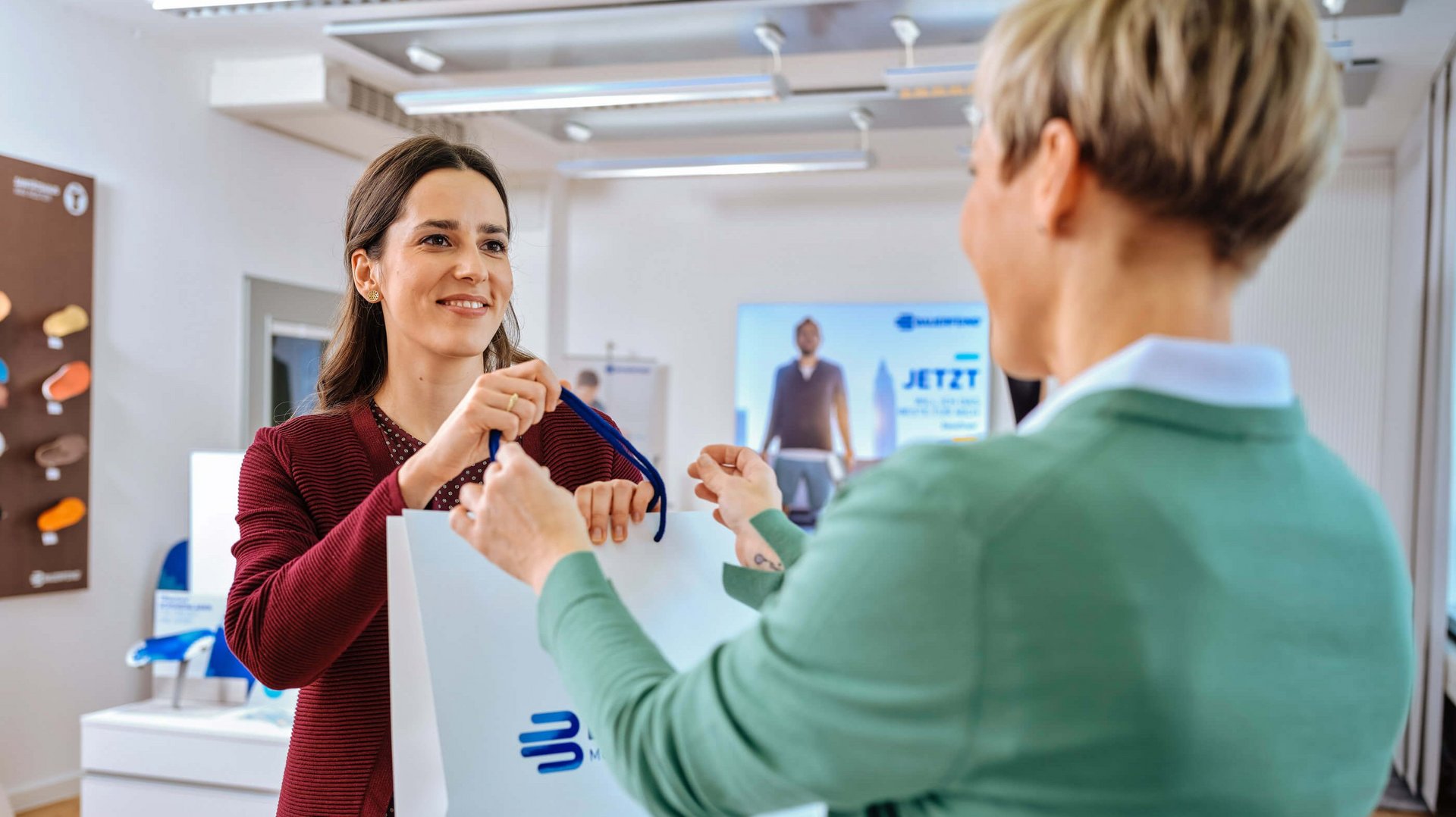 Te zien zijn twee vrouwen in een adviessituatie in de medische speciaalzaak over de hulpmiddelen van Bauerfeind.