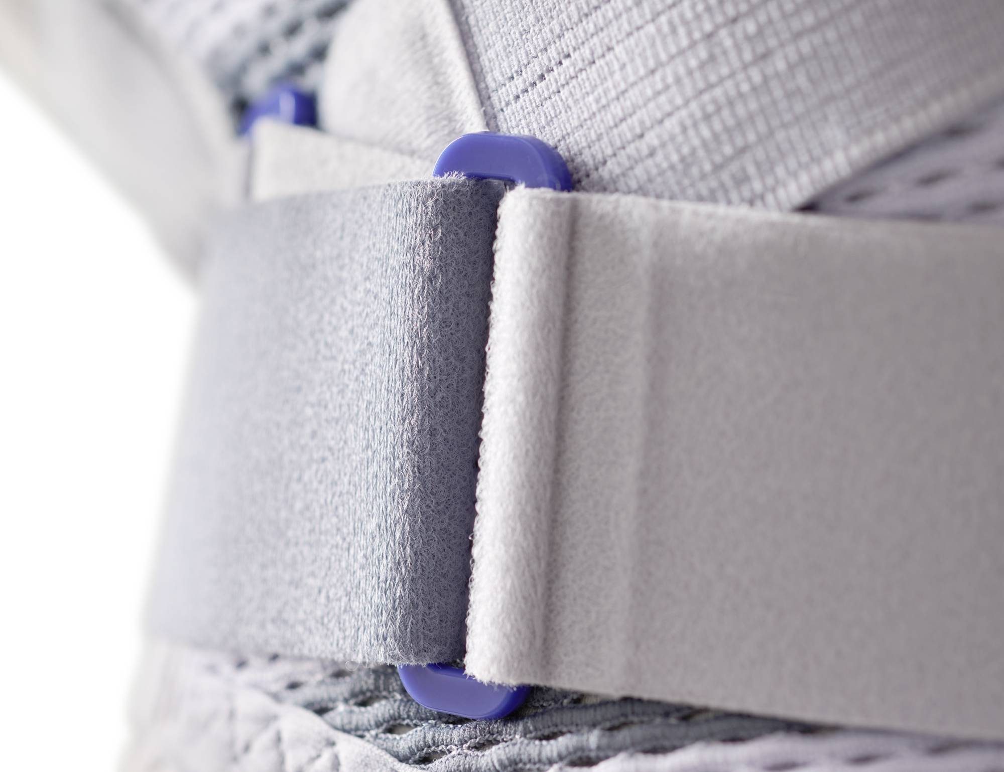Close-up van grijze stoffen banden met paarse kunststof knoppen en klittenbandsluiting.