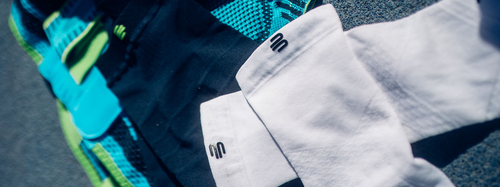 Close-up van verschillende Bauerfeind Sports producten, waaronder compressiekleding in verschillende kleuren. De afgebeelde textielproducten tonen het iconische logo van het merk.