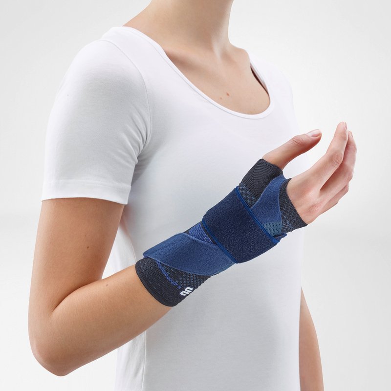 Vrouw draagt zwarte Bauerfeind ManuTrain polsbrace voor comfortabele polsondersteuning.
