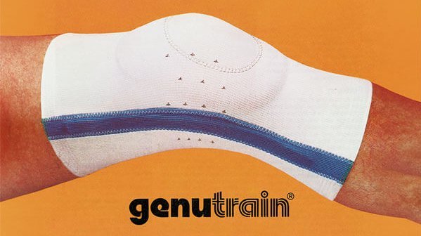 Advertentie voor een GenuTrain. De kniebandage met blauwe accenten, gedragen om een gestrekt been voor een oranje achtergrond. Onder de knie staat het merklogo genutrain®.