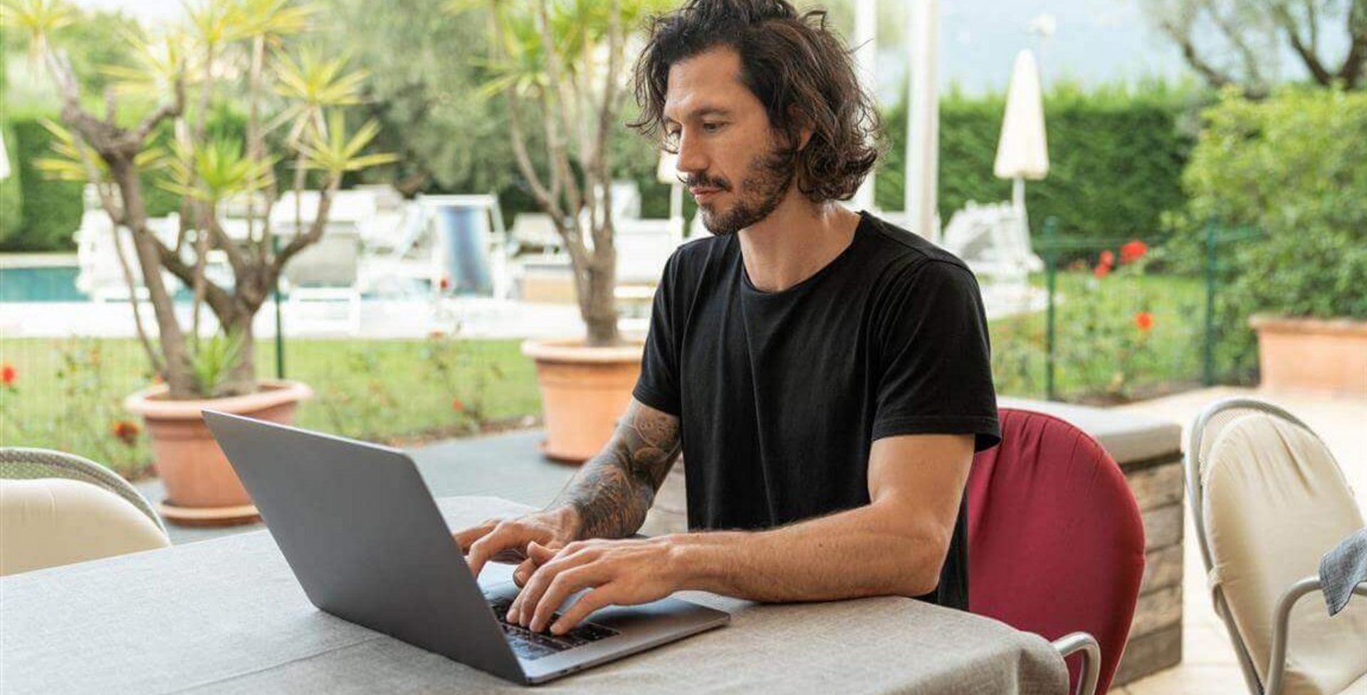 Afgebeeld is een jonge man die aan een laptop werkt. Eentonige bewegingen tijdens het werk kunnen muisarmklachten veroorzaken.