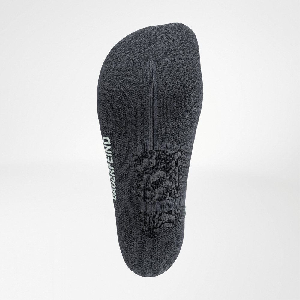 Onderzijde van een donkergrijze Bauerfeind Run Performance Midcut sok met antislip breistructuren en wit logo op de zool.