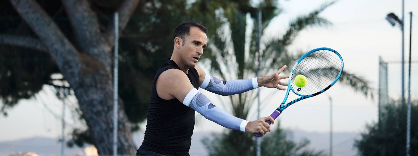 Tennisspeler met witte arm mouwen speelt tennis en verslaat een bal met de backhand
