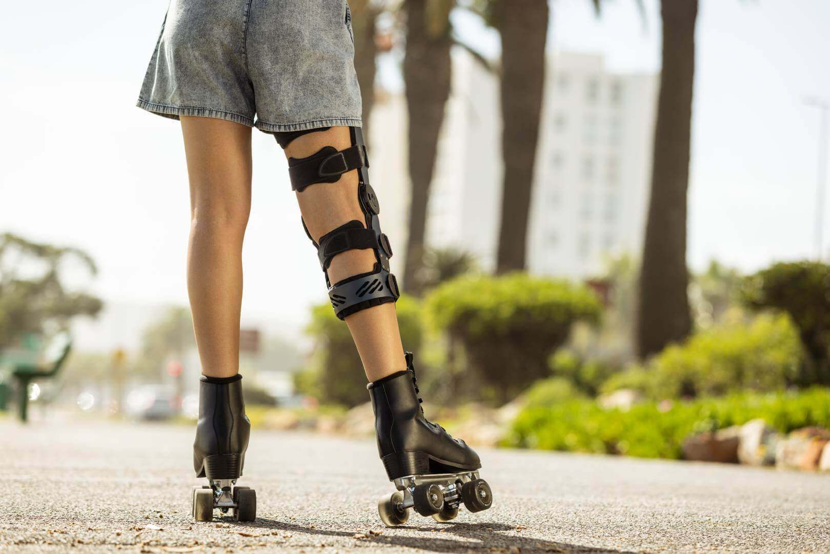 Uitsnede van een vrouw op rolschaatsen op een strandboulevard. Op haar knie draagt ze een SecuTec Genu. Deze orthese biedt onder andere ondersteuning na een Unhappy Triad.