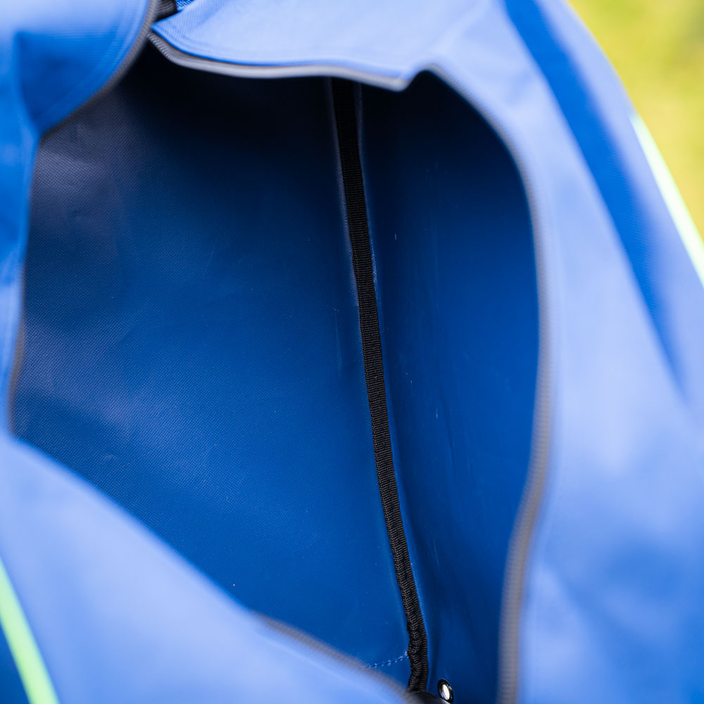 Een close-up van het interieur van een blauwe tas met een zwarte ritssluiting. Het interieur is leeg en de stofdetails zijn zichtbaar.