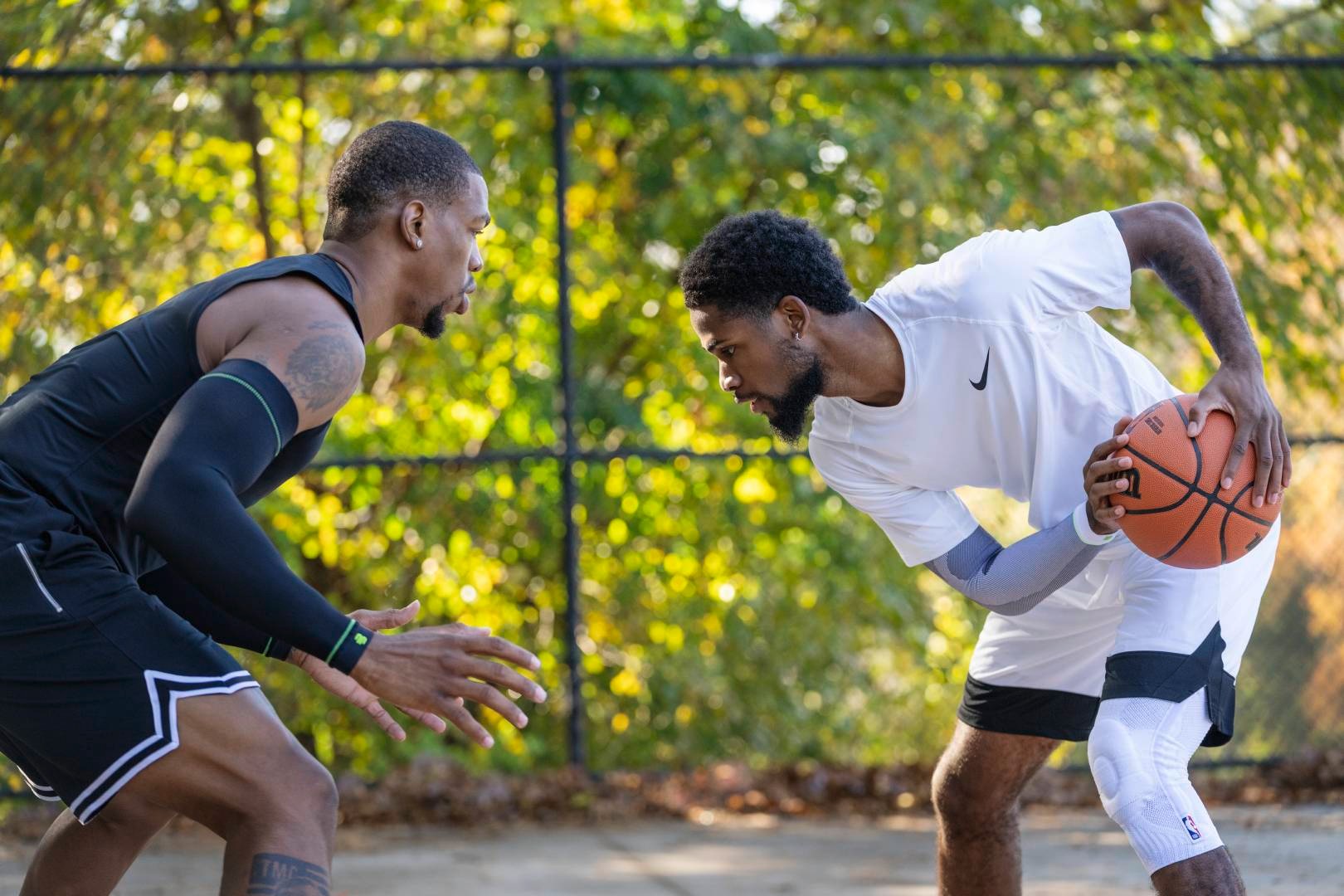 Streetball -speler in witte spelkleding probeert zijn tegenstander te spelen in zwarte spelkleding