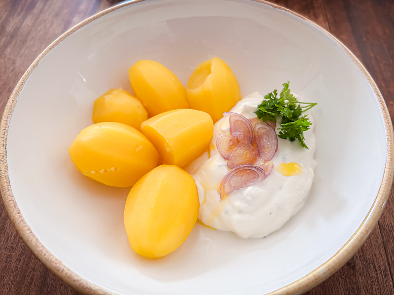 Een bord met gekookte aardappelen en kwark, een gezonde en licht verteerbare maaltijd voor carbo-loading voor een halve marathon.