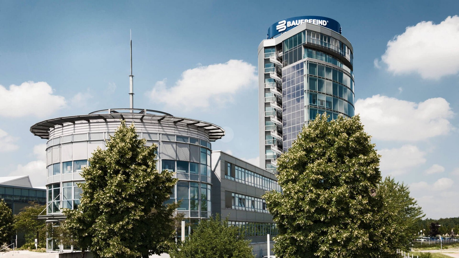 Blik op de moderne Bauerfeind-toren in Zeulenroda: een gebouw met meerdere verdiepingen, een strakke architectuur van glas en staal, omgeven door groen aangelegde buitenruimtes.