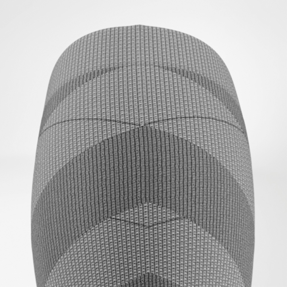 Bovenaanzicht van het bovenste deel van de ski-compressiekous voor dames met geribde structuur en graduele compressiezones rond de knie.