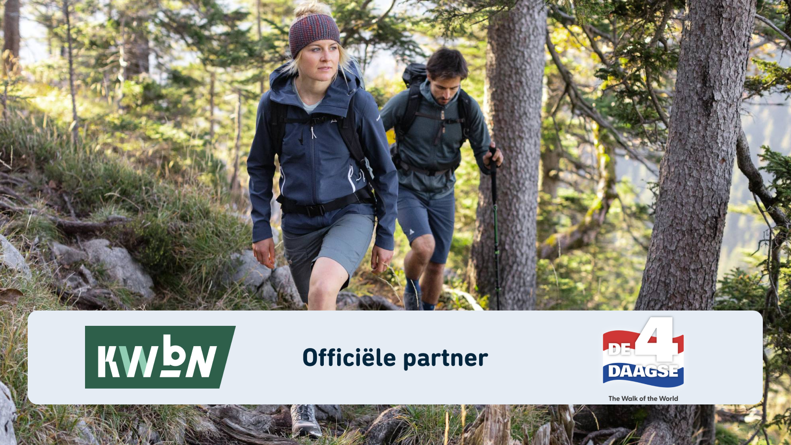 Twee wandelaars met rugzakken in technische outdoor-kleding lopen over een smal bospad. Op de voorgrond staan het KWBN-logo en de vermelding van het partnerschap met de 4Daagse.