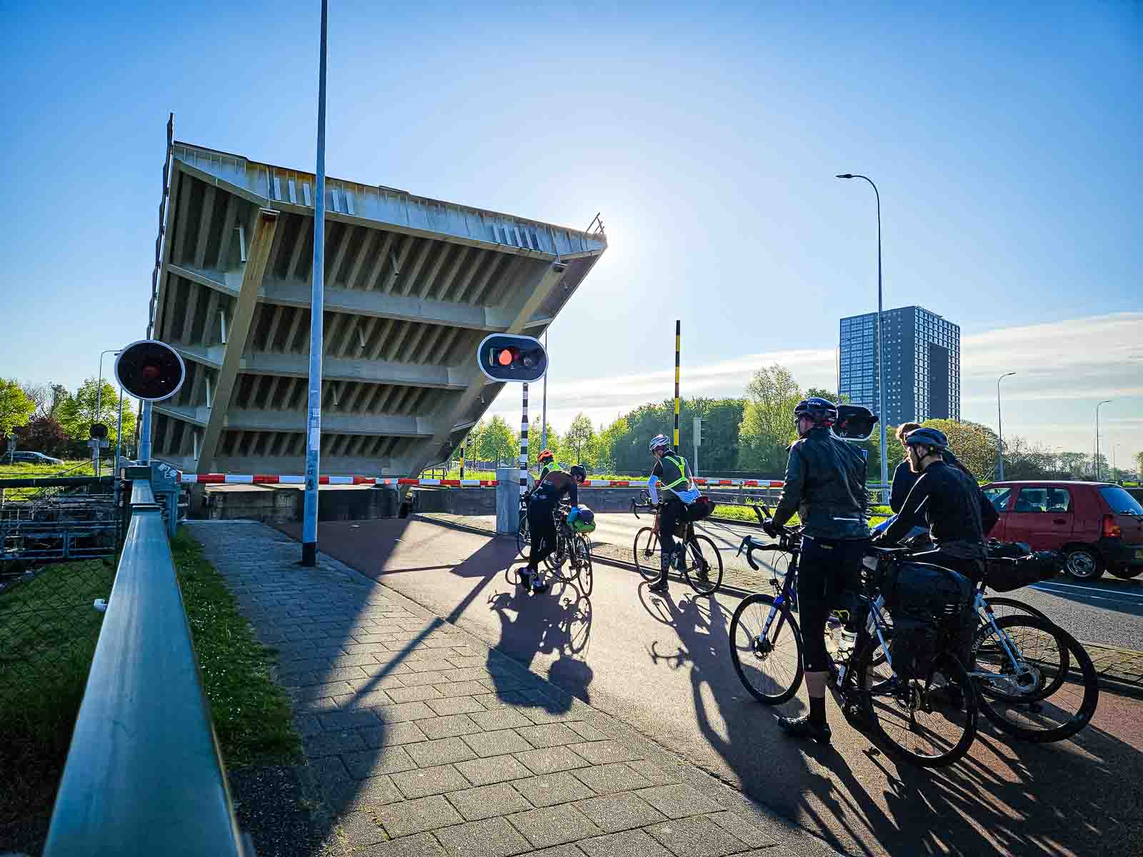 Verschillende deelnemers aan de Race om Nederland staan te wachten bij een verhoogde brug.