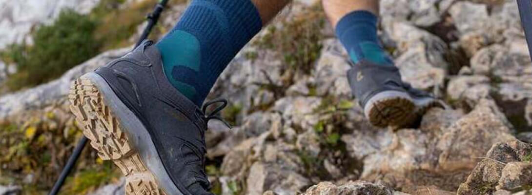 Persoon gaat een berg op over stenen en draagt ​​medium -lengte wandelsokken
