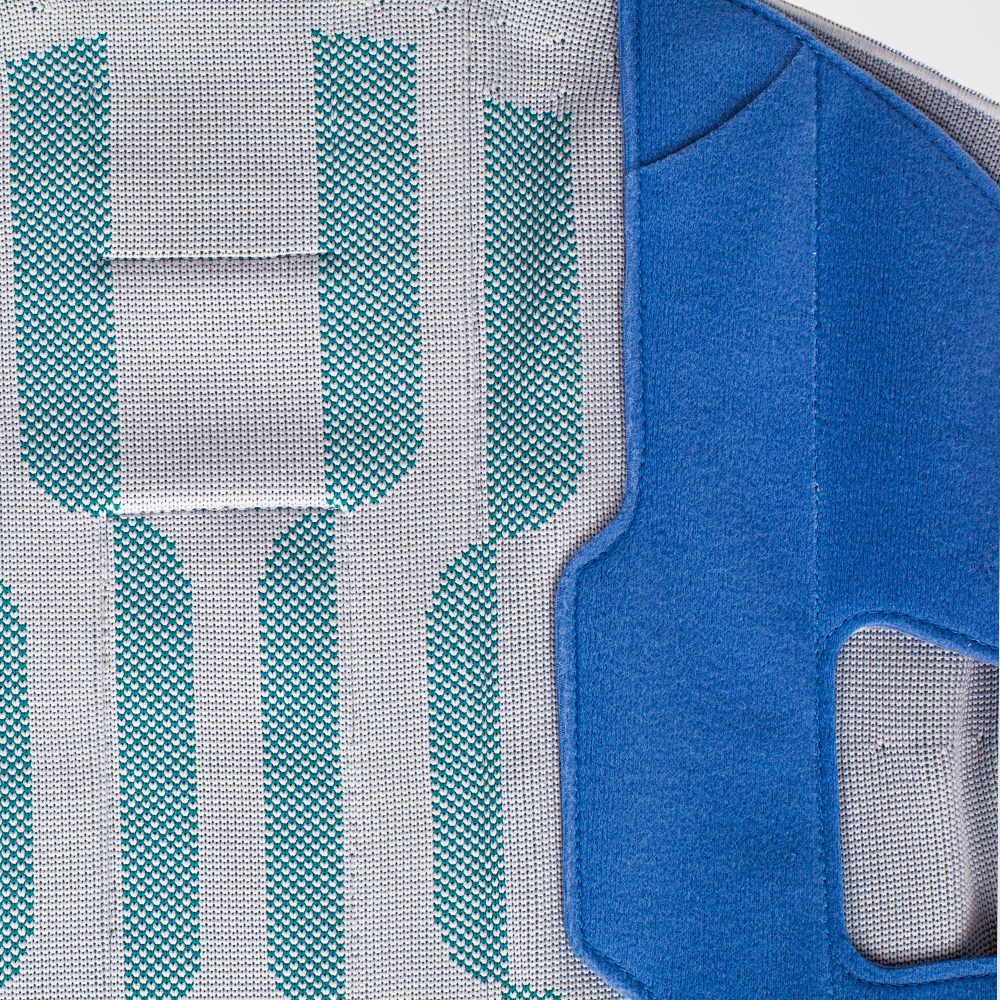 Close-up van grijze meshstof met turquoise strepen en een blauw gewatteerd textieldeel met stiknaden.