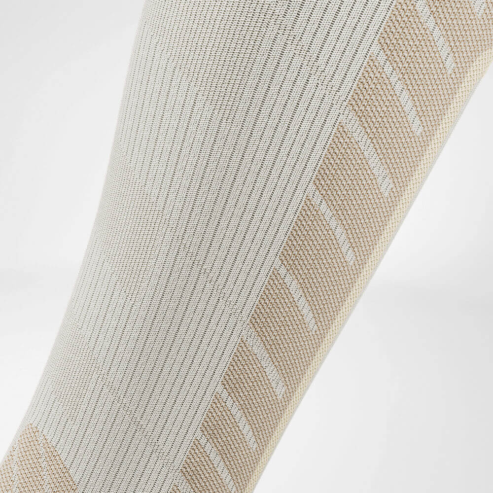 Detail van de kuitcompressiezone van de beige sportsok voor skiën met merinowol