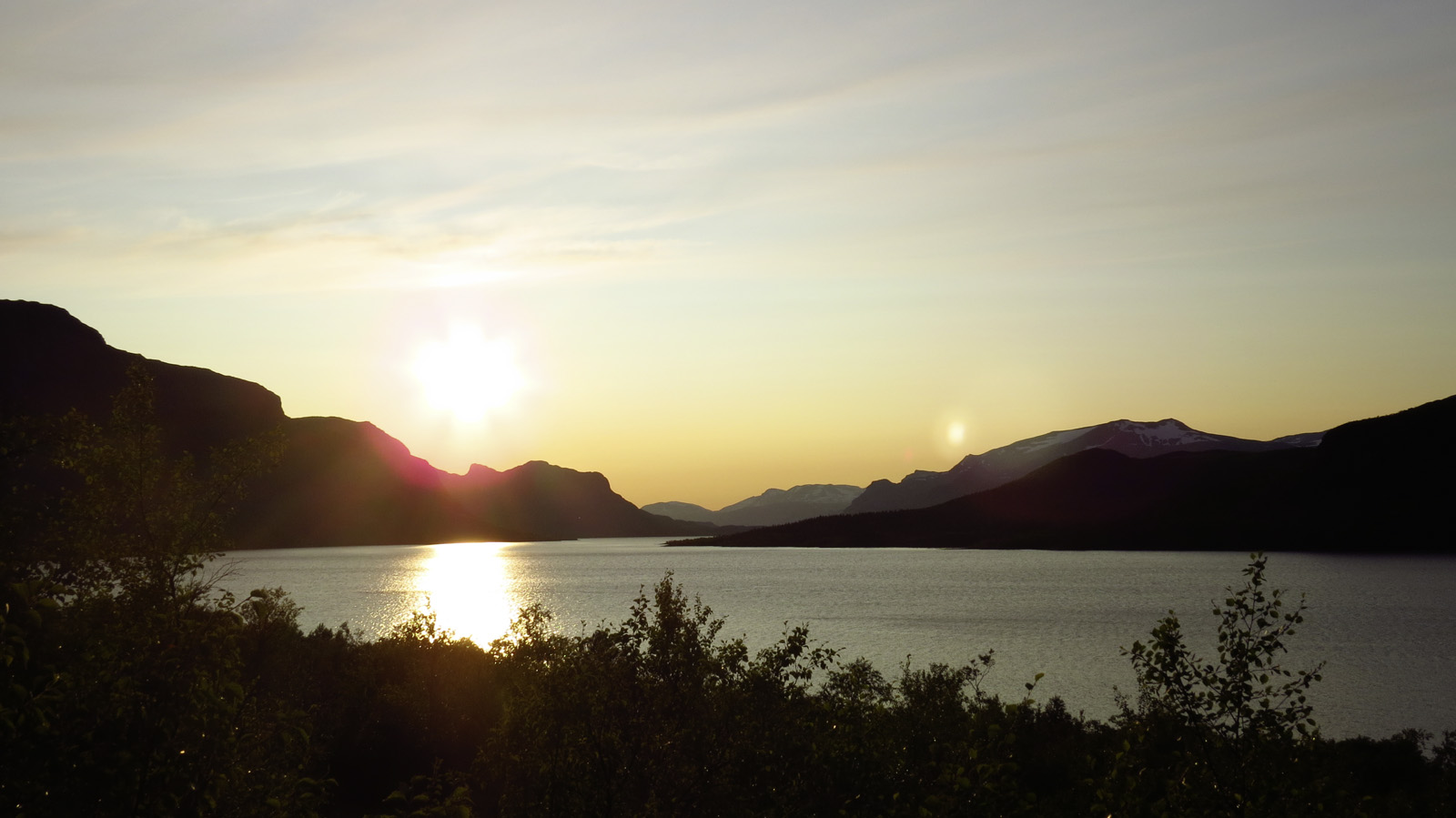 Panorama van een meer met bergen bij zonsondergang