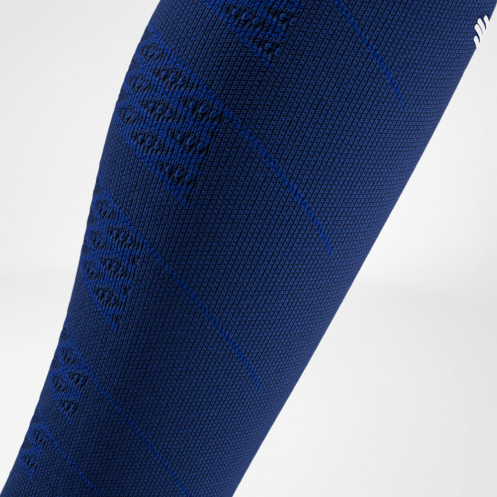 Close-up van een marineblauwe compressiesleeve met fijne structuur en ingebreide compressiezones op de kuit.