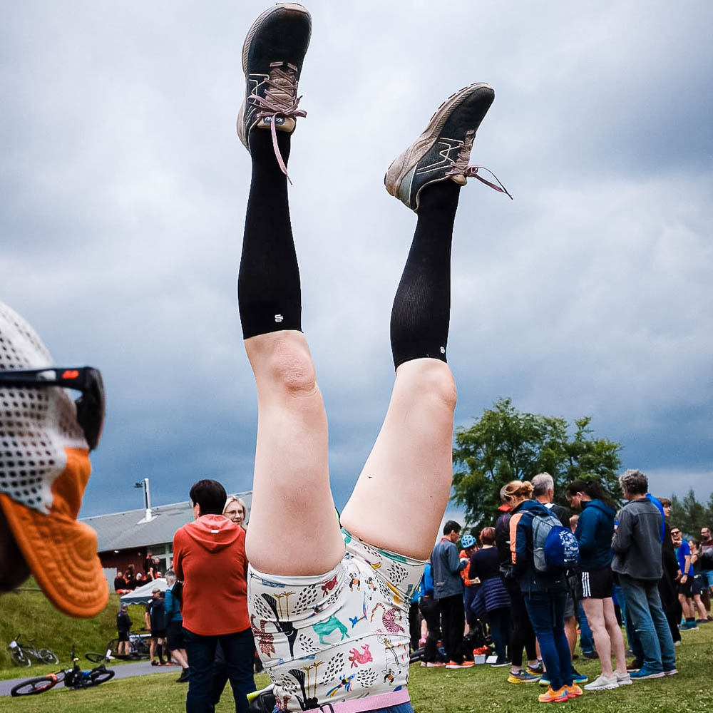 Een vrouw in een korte sportshort en kniekousen doet een handstand