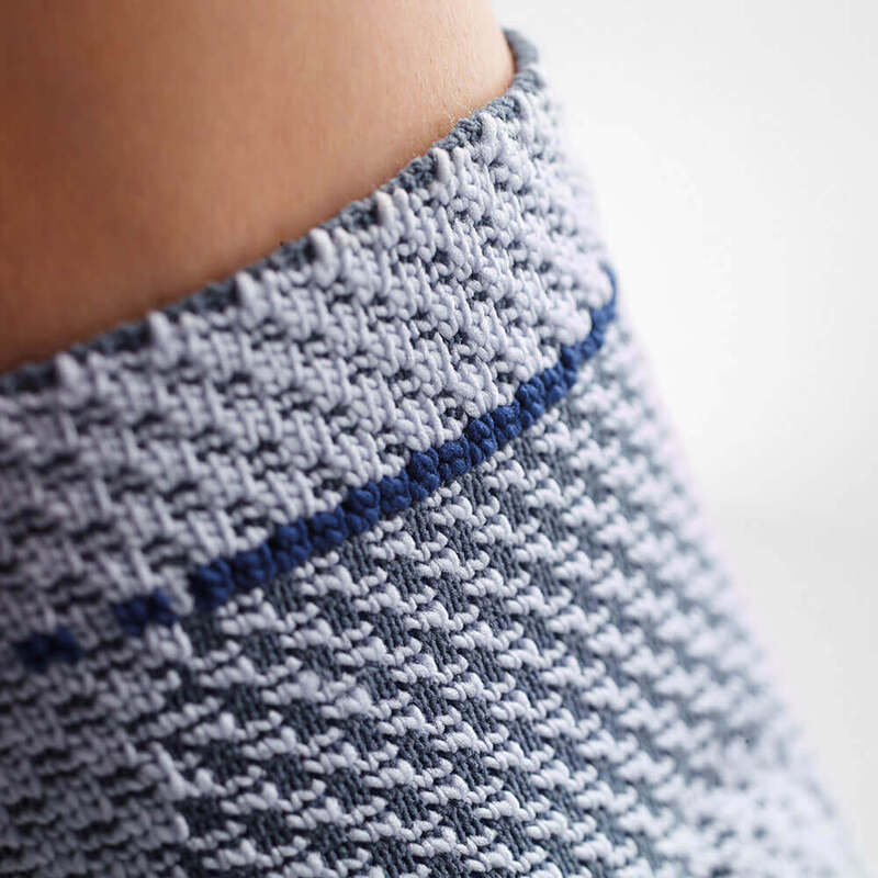 Close-up van gebreide rand van de MalleoTrain enkelbrace met blauwe streep en fijne textuur.