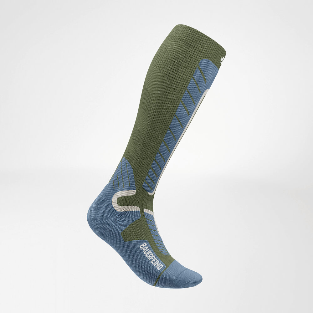 Zijaanzicht van een groene kniehoge ski-compressiesok met versterkt breipatroon voor optimale stabiliteit en comfort tijdens de wintersport.