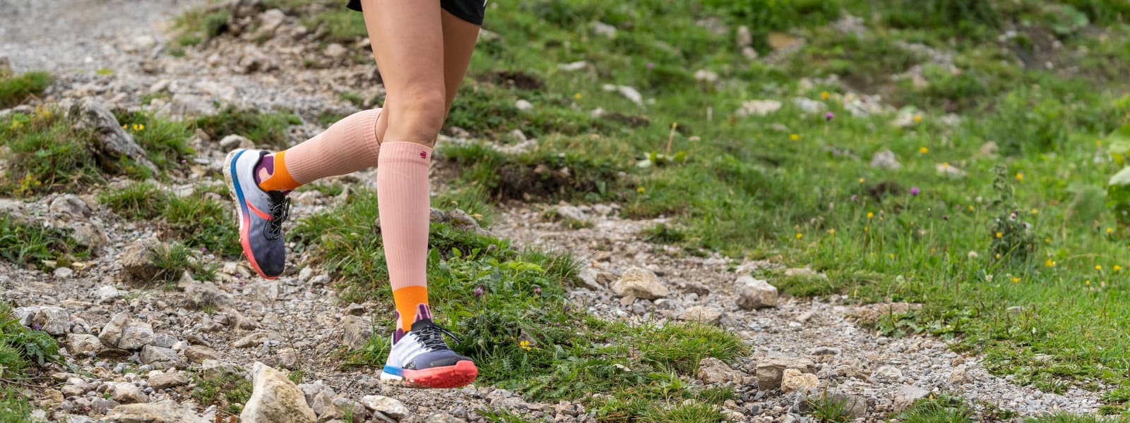 De hardloper rent op een berg en draagt ​​de trailrunsokken in de kleuren perzik