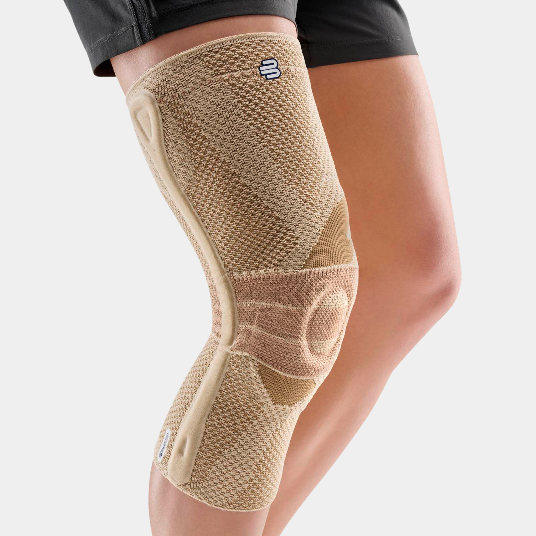 Beige GenuTrain P3 kniebrace op het been met zijstabilisator en compressiezones.