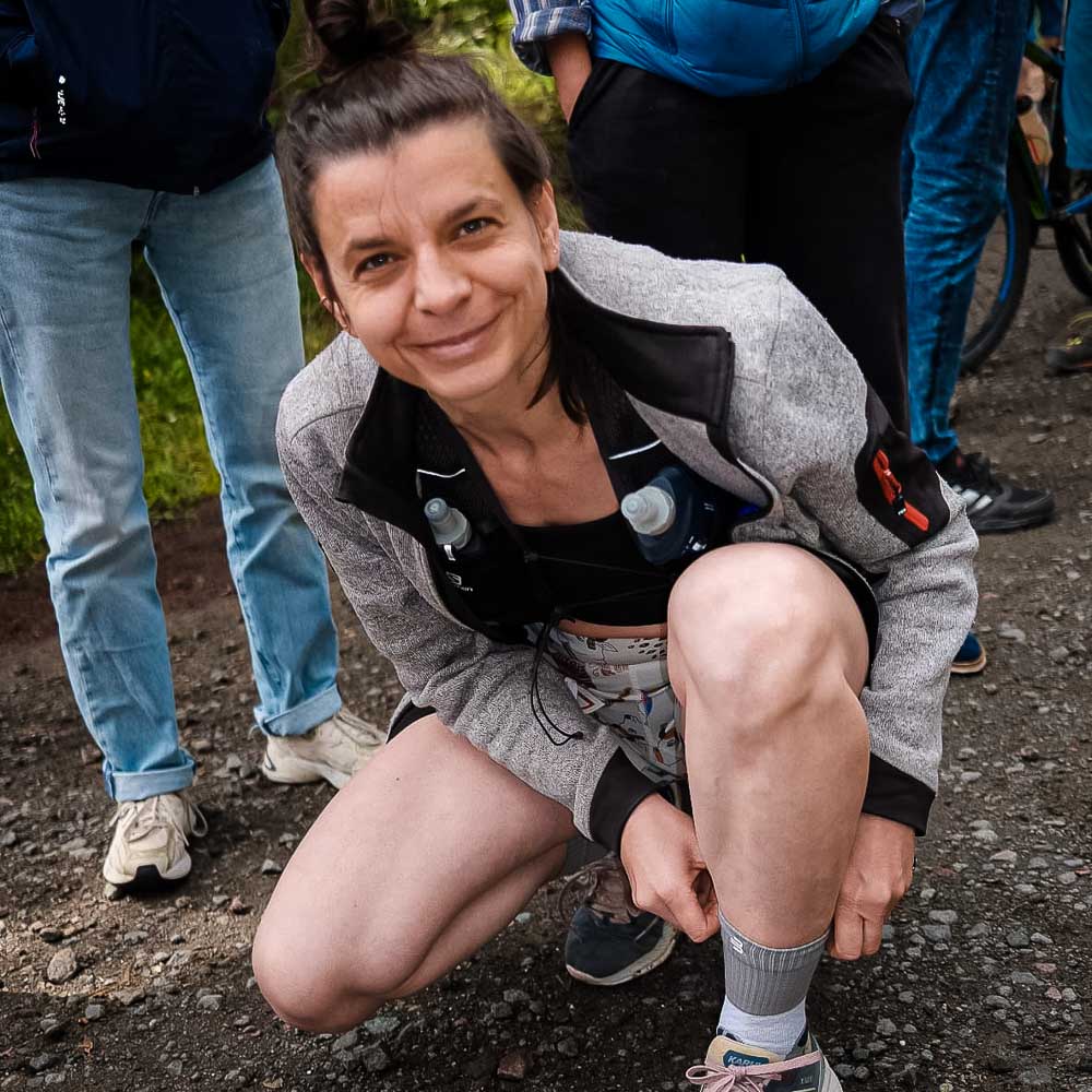 Een vrouw lacht naar de camera terwijl ze haar halflange sokken verstelt