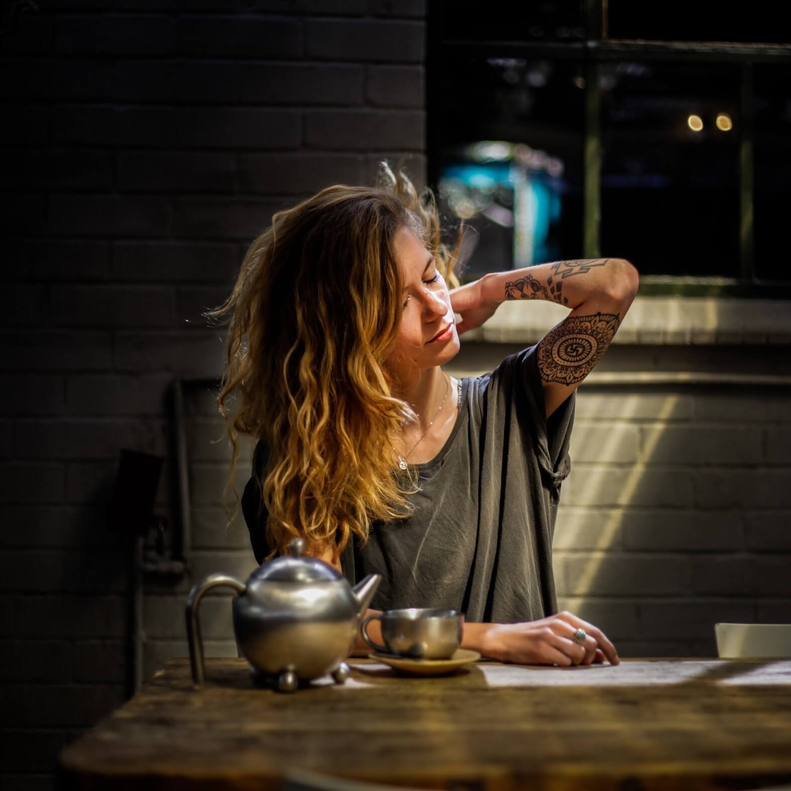 De afbeelding toont een vrouw aan de keukentafel. Ze oogt heel gestrest en pakt zich aan de rug vast. Rugpijn kan een aanleiding voor stress zijn.