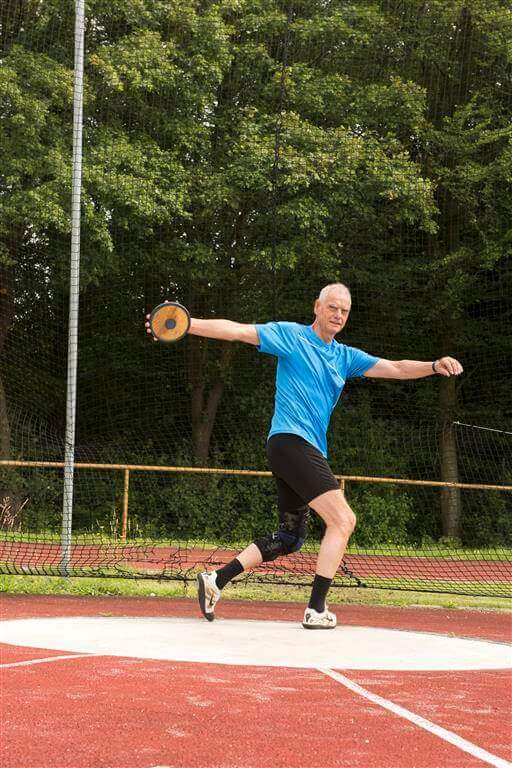 De afbeelding toont sporter en artrosepatiënt Wilhelm Kraatz met de knieorthese GenuTrain OA tijdens het discuswerpen.