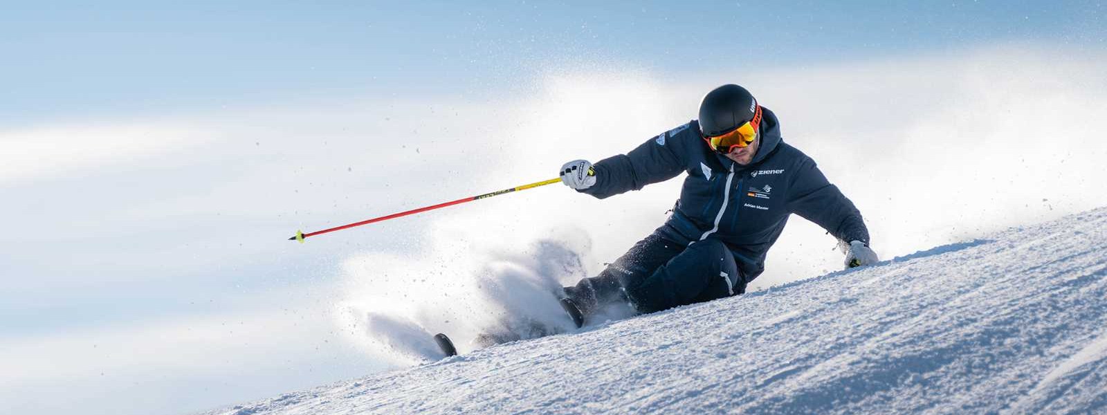 Skiërs in een donker pak in een extreme helling bij het vertrek