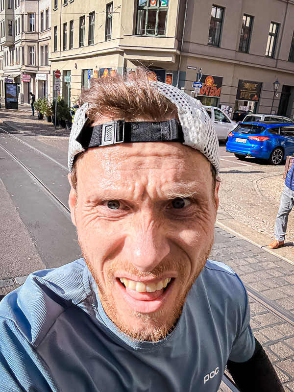 Een uitgeputte loper ploetert door de laatste kilometers van een halve marathon. Ondanks vermoeidheid zet hij door om de race te voltooien, ook al lijkt een persoonlijk record onhaalbaar.
