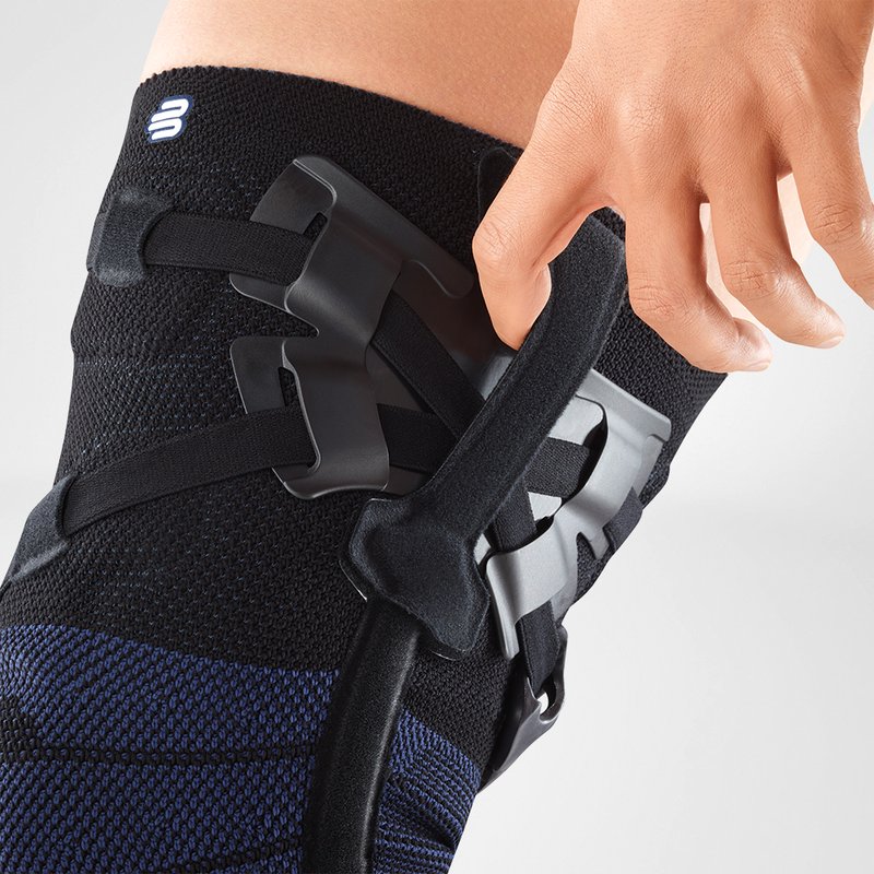 Close-up van persoon die zwarte GenuTrain OA unloader kniebrace met straps verstelt.