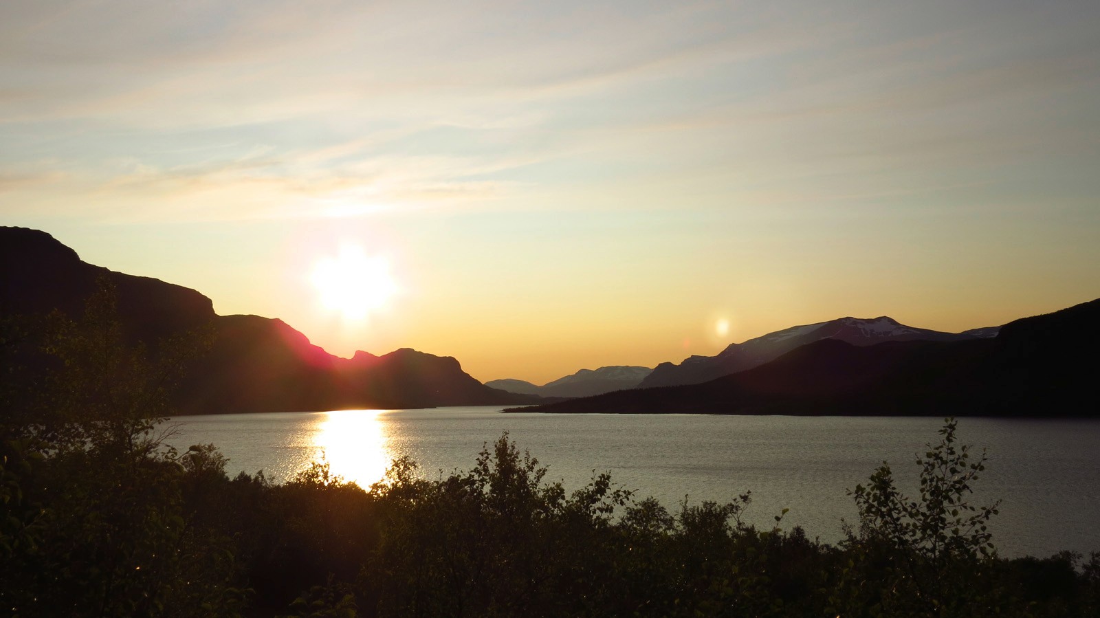 Panorama van een meer met bergen bij zonsondergang