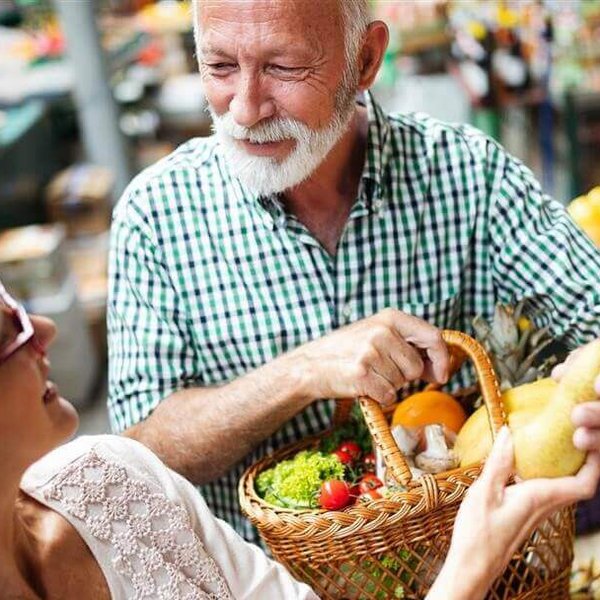 Op de afbeelding staan een man en een vrouw bij een marktkraam. Ze willen met gezonde voeding hun artrose bestrijden.