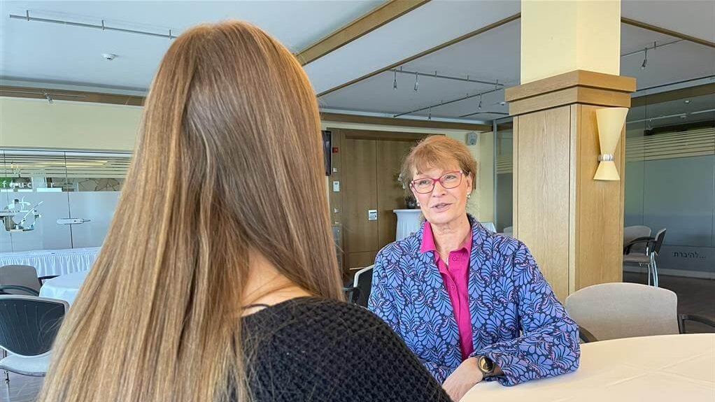 Psychologe Bettina Kappe in een adviesgesprek over het thema mental load en aandacht, zittend aan een tafel in een moderne vergaderruimte, in gesprek met een vrouw die van achteren te zien is.