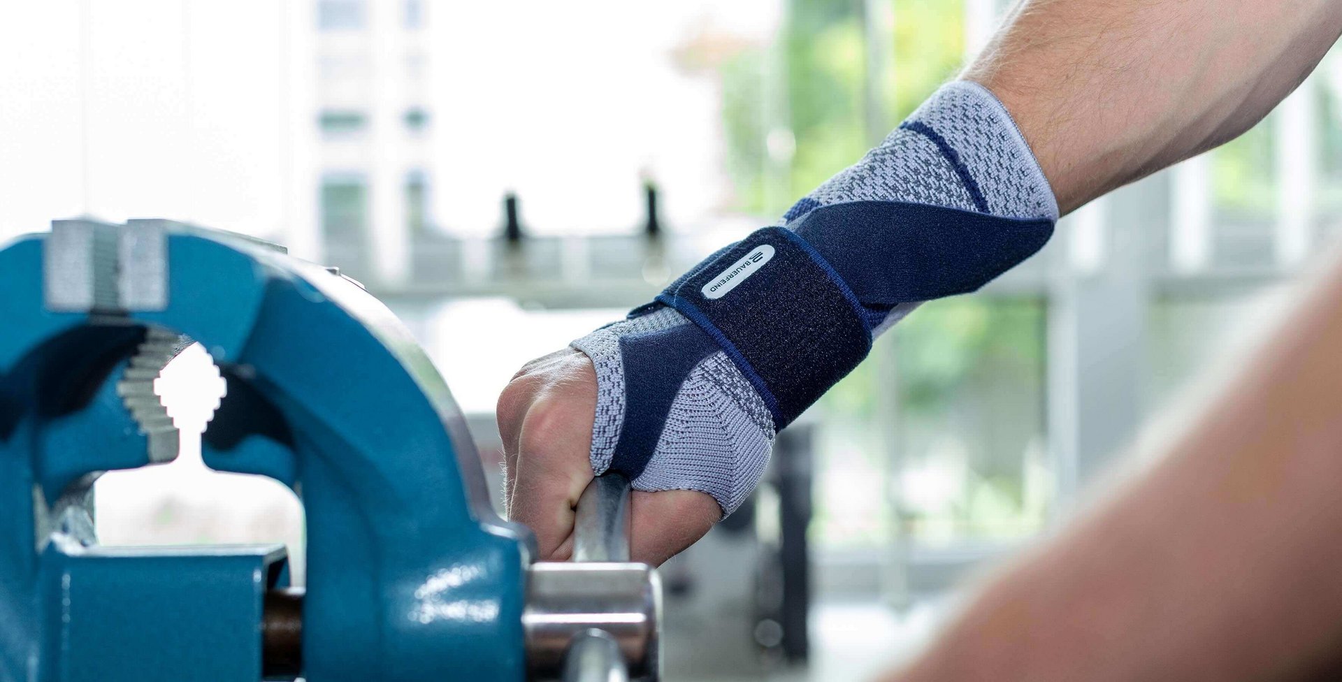 Beelduitsnede van een man die aan een bankschroef werkt. Aan zijn rechterhand draagt hij een ManuTrain bandage van Bauerfeind. Die biedt onder andere steun bij een peesschede-ontsteking.